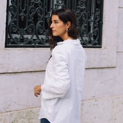 Blusa branca de manga comprida com gargantilha e punhos de renda em cenário urbano