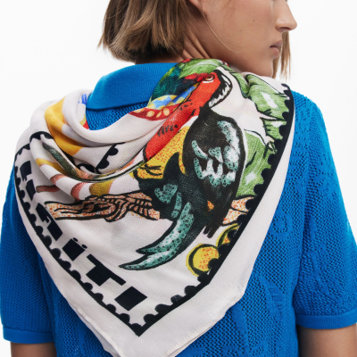 Lenço triangular colorido em tecido branco sobre camisola azul de malha