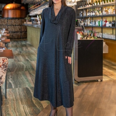 Vestido preto cintilante com gola drapeada e mangas compridas num bar interior