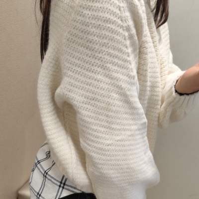 Casaco branco de malha texturizada sobre camisa xadrez preta e branca e calças jeans pretas