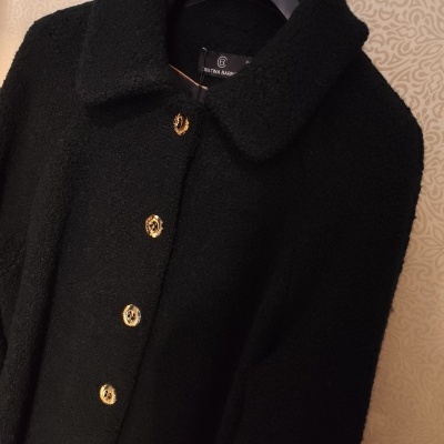 Casaco preto felpudo com botões dourados em cabide preto Cristina Barros