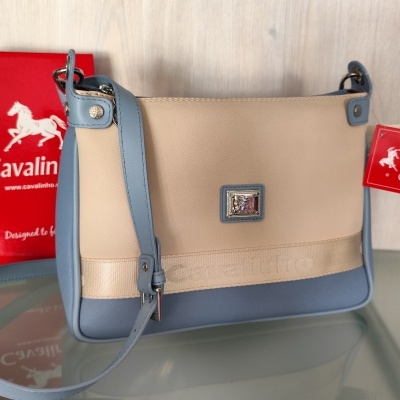 Mala Cavalinho bege e azul claro com etiqueta vermelha e caixa vermelha ao fundo