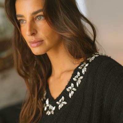 Mulher com camisola preta de malha com pedras brilhantes no decote