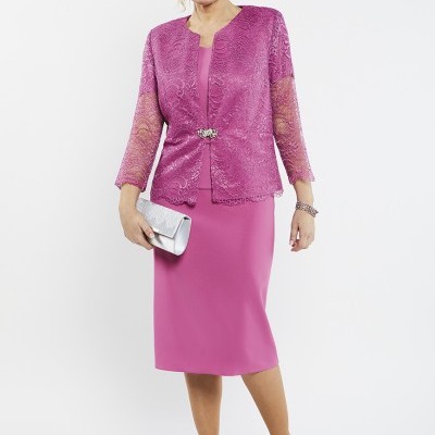 Mulher veste vestido rosa com casaco de renda rosa e sapatos prateados, segura carteira prateada
