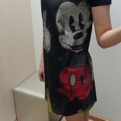 Vestido preto com estampa do Mickey Mouse, pessoa em pé em ambiente interior.