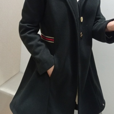 Casaco comprido preto com botões dourados e detalhe às riscas laterais