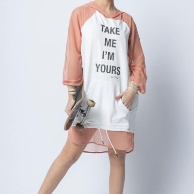 mulher com vestido branco e rosa claro com texto e tênis brancos segurando um skate