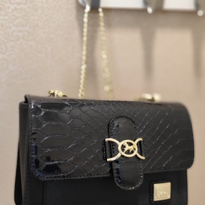 Mala preta com padrão de pele de cobra e fecho dourado com design entrelaçado