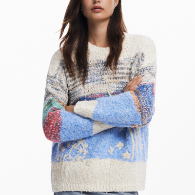 Mulher a usar camisola de malha colorida e saia cinzenta, fundo branco