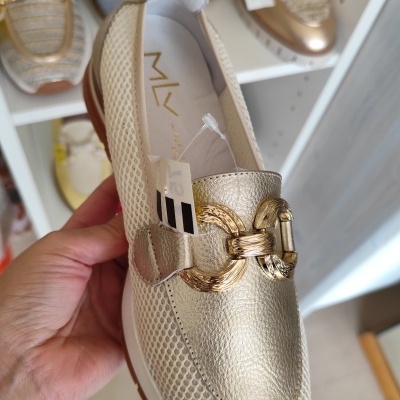 Mocassim dourado com fivela dourada e textura em rede branca nas laterais