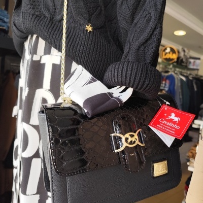 Bolsa preta de senhora com fecho dourado e etiqueta vermelha Cavalinho