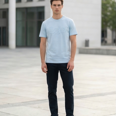 Homem com t-shirt azul clara, calças pretas e sapatilhas brancas em espaço urbano