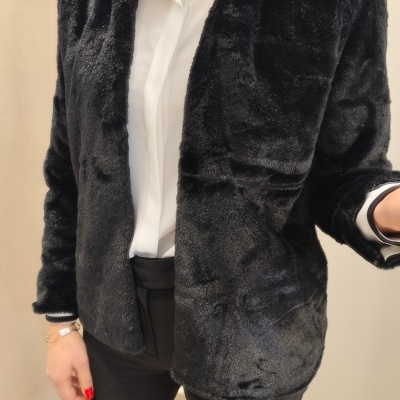 Casaco preto de pelo sintético usado por pessoa com camisa branca e calças pretas