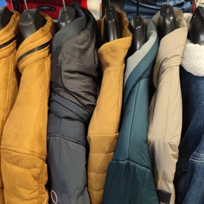 Casacos diversos pendurados em cabides em várias cores e texturas.
