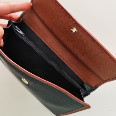 Carteira verde e castanha aberta com interior castanho e fecho de botão.