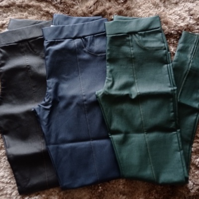 Três pares de calças justas em preto, azul escuro e verde escuro sobre tapete castanho claro