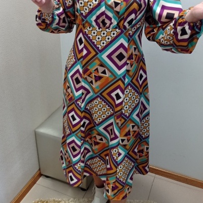 Vestido midi colorido com padrão geométrico e botas brancas