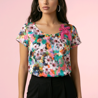 Mulher com t-shirt floral colorida e calças pretas em fundo rosa