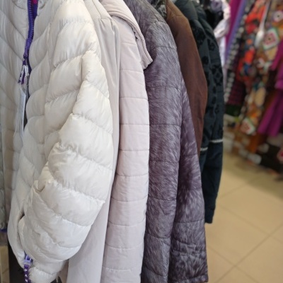 Casacos acolchoados de várias cores pendurados numa loja de roupa