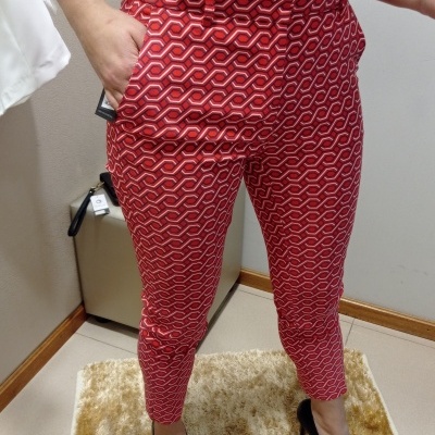 Calças vermelhas com padrão geométrico usadas com camisa branca e sapatos pretos