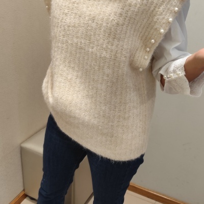 Colete bege de malha com pérolas e camisa branca com punhos bordados