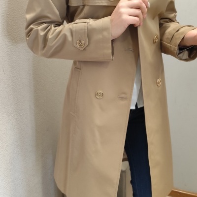 Casaco bege comprido com botões dourados em ambiente interior