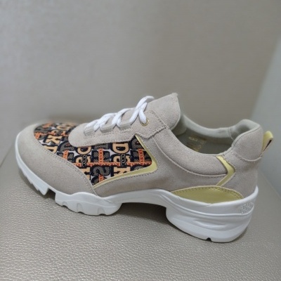Tênis desportivo bege com padrões geométricos em preto, castanho e laranja e sola branca