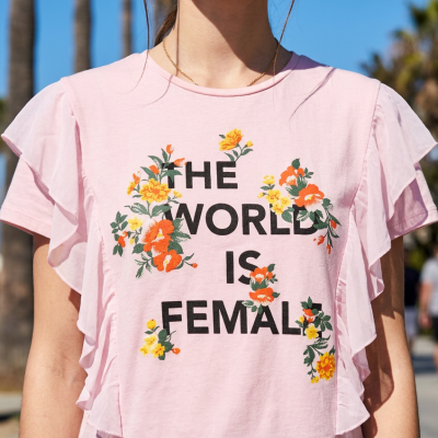 T-shirt rosa clara com texto e flores, com volantes nas laterais.