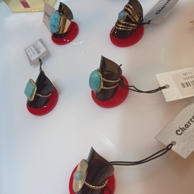 Anéis dourados com pedras azuis em suportes pretos com base vermelha