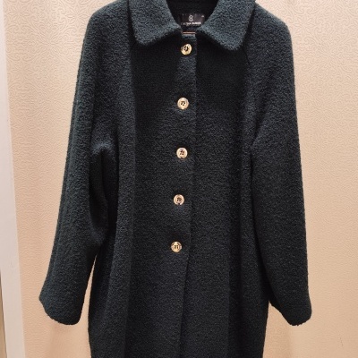 Casaco preto felpudo com botões castanhos pendurado num cabide preto