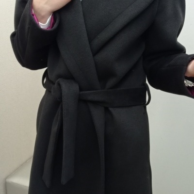 Casaco comprido preto com cinto amarrado usado por pessoa