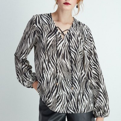 Blusa feminina com padrão animal print preto e branco com mangas longas e decote em V, usada com calções pretos