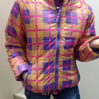 Casaco acolchoado amarelo, roxo e rosa com padrão geométrico e fecho roxo