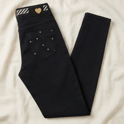 Calças pretas com bolso decorado com tachas e etiqueta com coração dourado