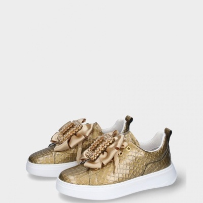 Tênis dourados com padrão pele de crocodilo e laço decorativo com pérolas