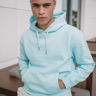 Homem jovem com sweatshirt azul claro sentado num espaço exterior moderno.