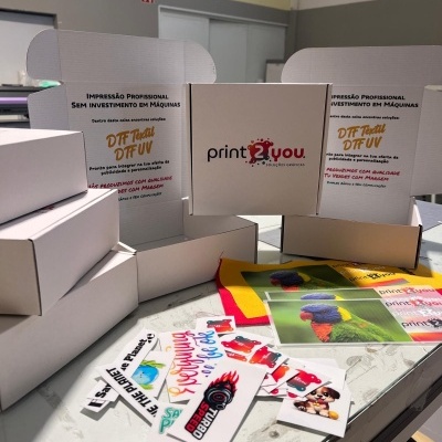 Caixas de cartão branco com textos promocionais e várias etiquetas coloridas sobre uma mesa.