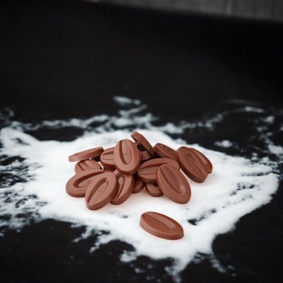 Pastilhas de chocolate marrom sobre fundo preto com líquido branco.