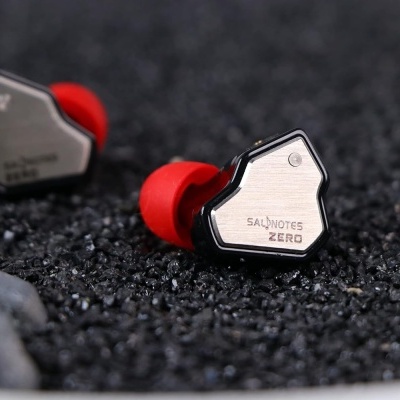 Auriculares Salnotes Zero com detalhes metálicos e vermelhos numa superfície de pedra negra