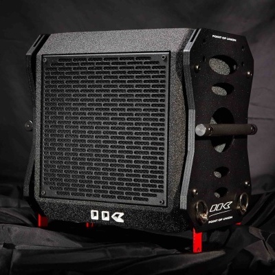 Amplificador de som preto com textura metálica e grelha frontal com padrão de furos