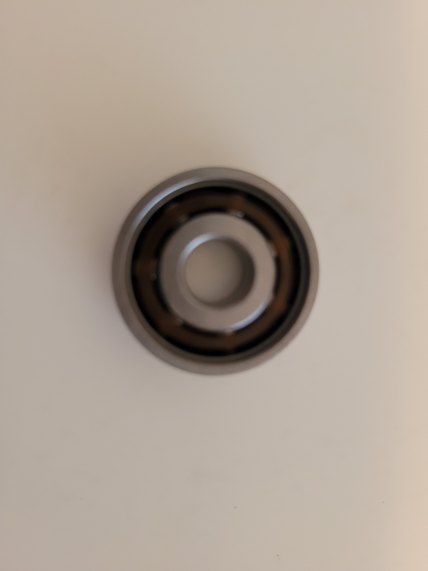 Rolamento metálico circular com partes metálicas e interiores escuras sobre fundo branco