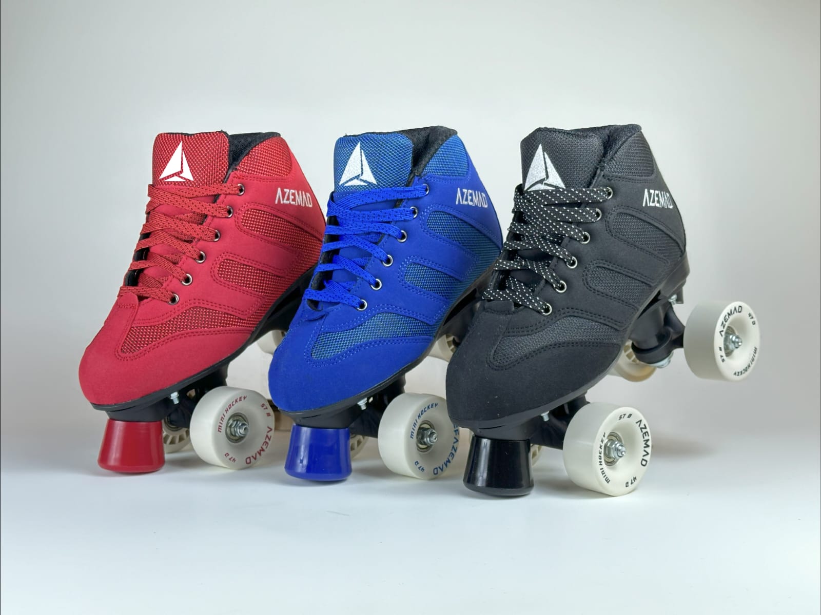 Três patins de rodas nas cores vermelho, azul e preto, com rodas brancas e texto AZEMAD