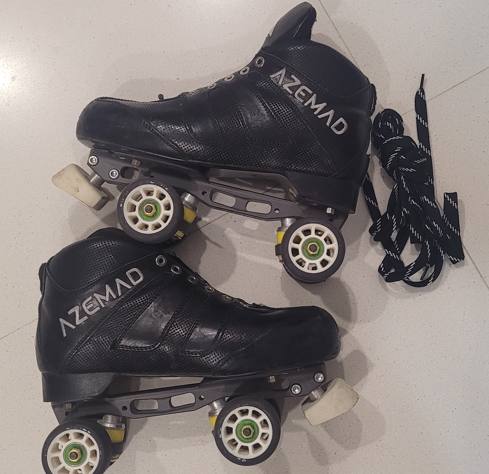 Patins quad preto AZEMAD com atacadores pretos e brancos no chão branco