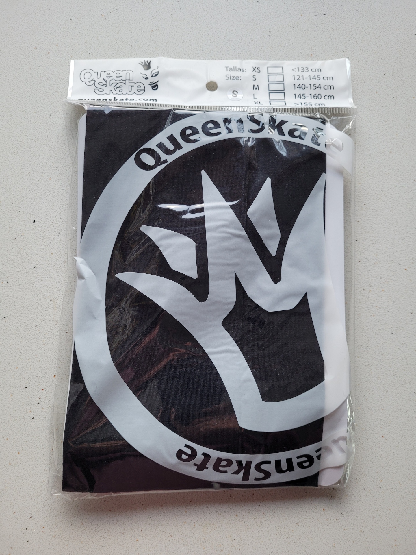 Embalagem de roupa preta com estampa branca e logotipo com texto Queen'skate