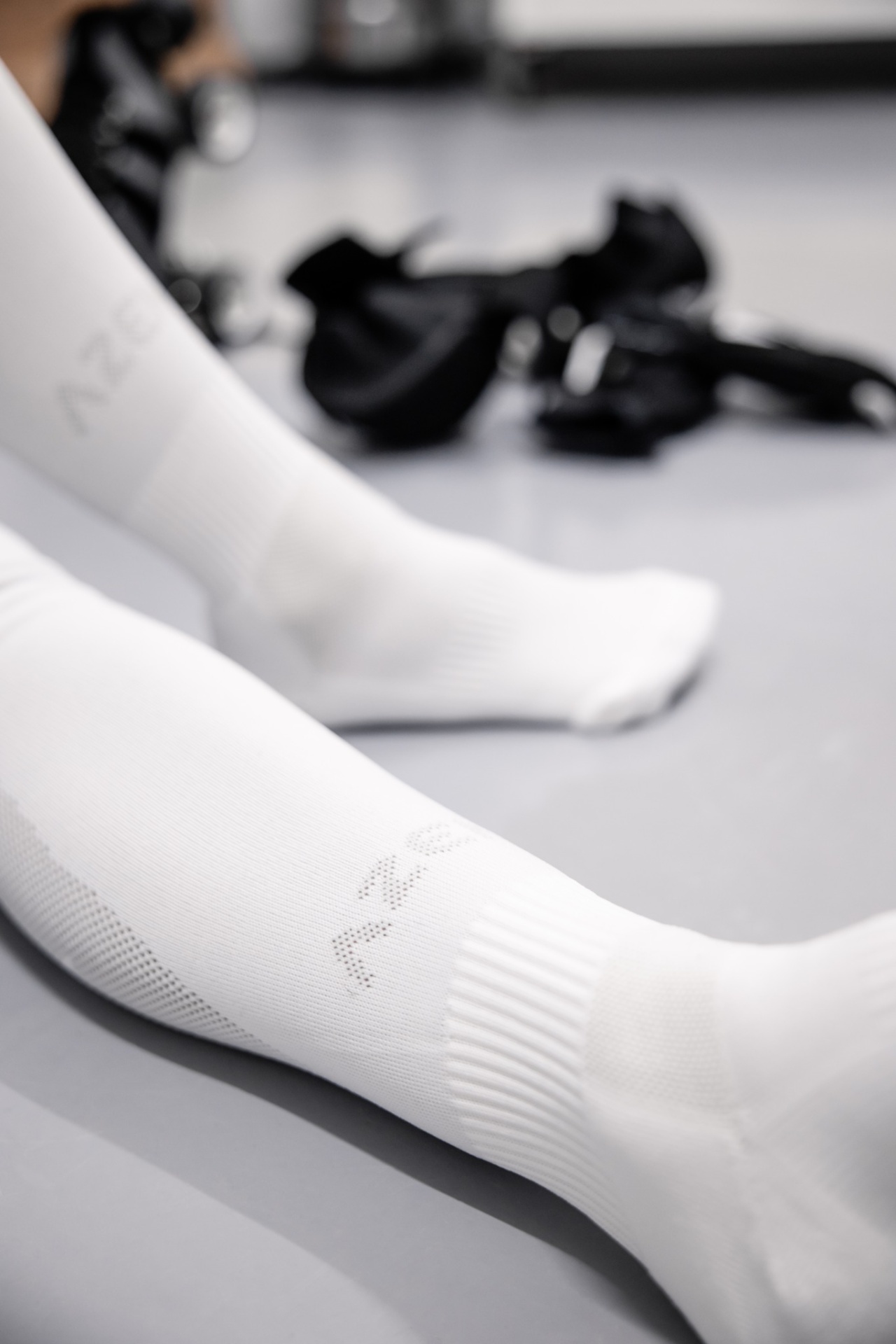 Meias desportivas brancas com texto AZEY em fundo cinza