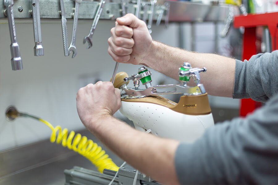 Mãos a trabalhar numa máquina ortopédica numa oficina com ferramentas