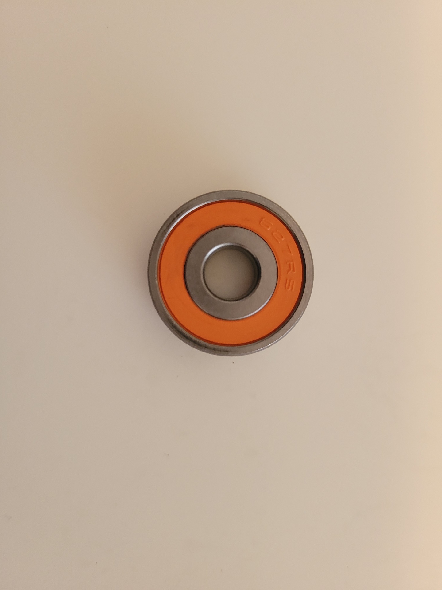 Rolamento metálico com anel laranja e números gravados