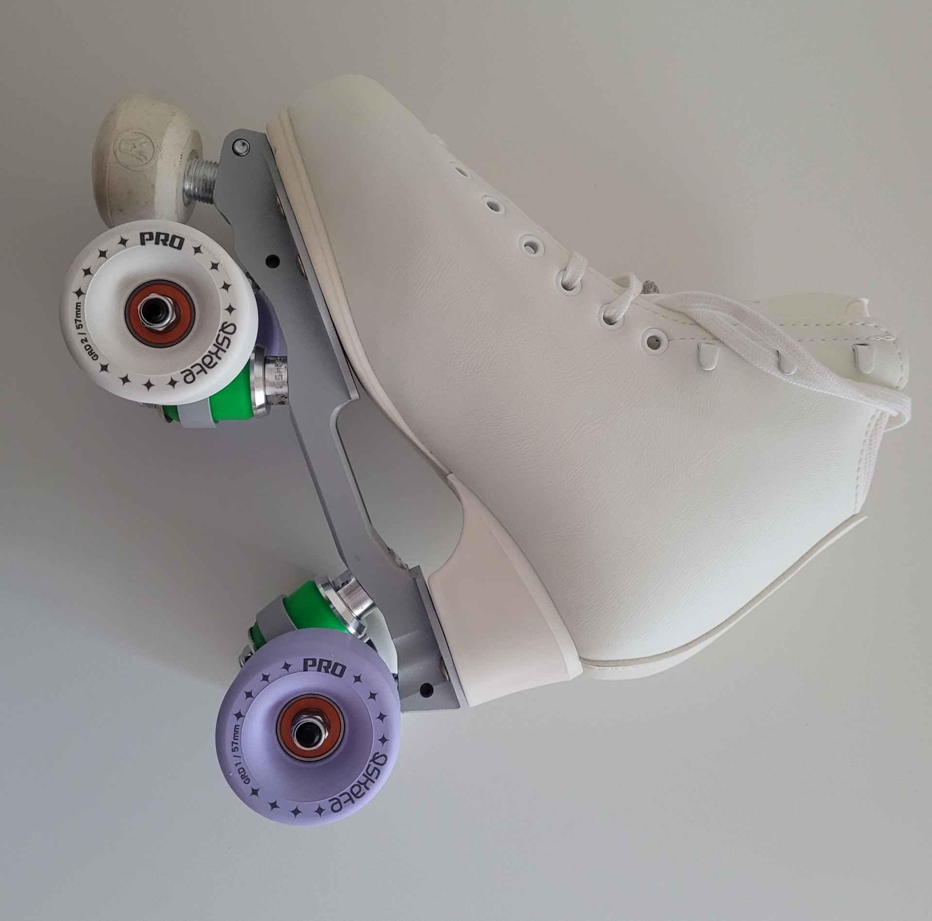 Patim de quatro rodas branco com rodas coloridas em verde, lilás e branco