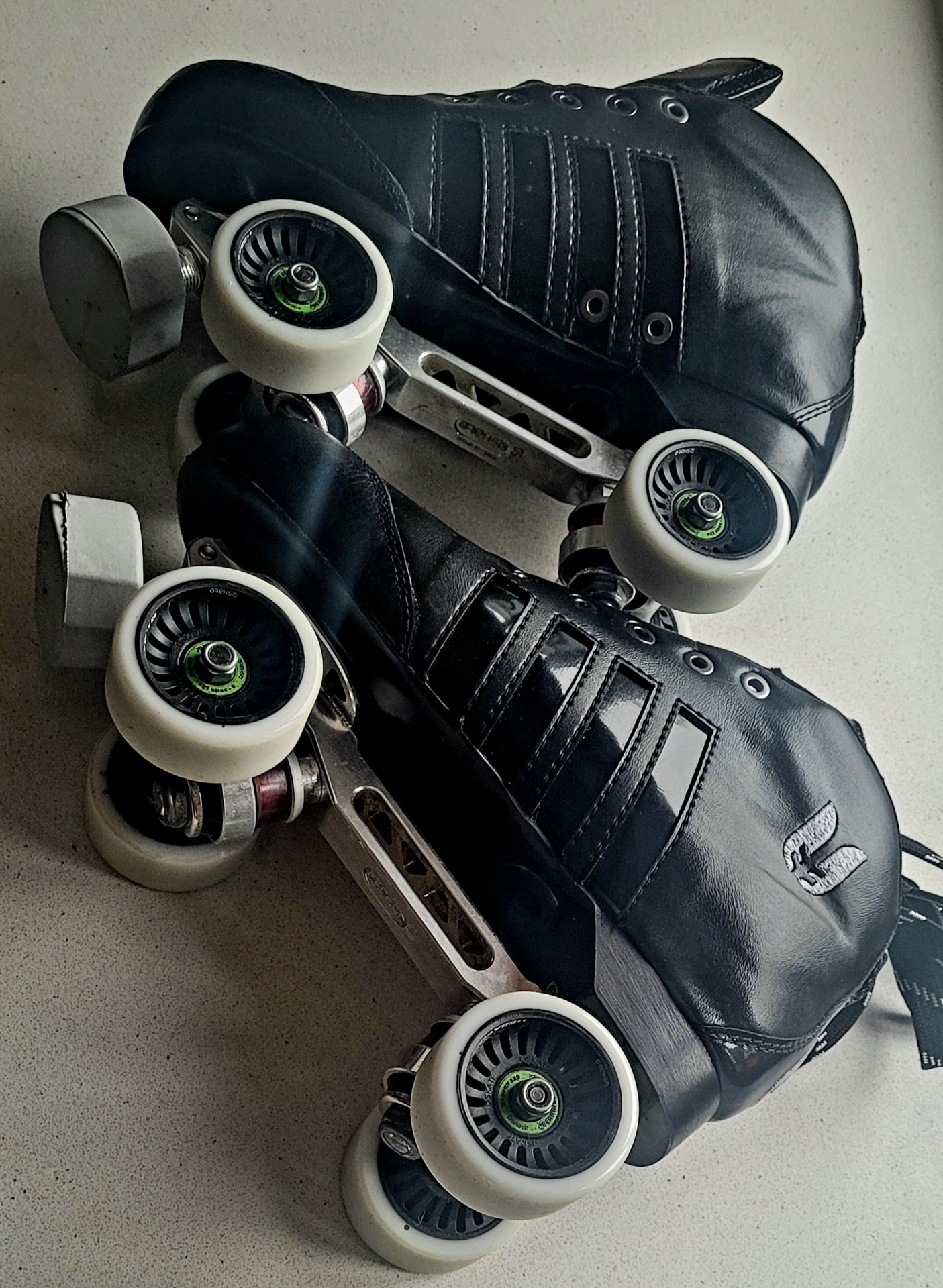 Patins de rodas pretos com rodas brancas sobre superfície cinza