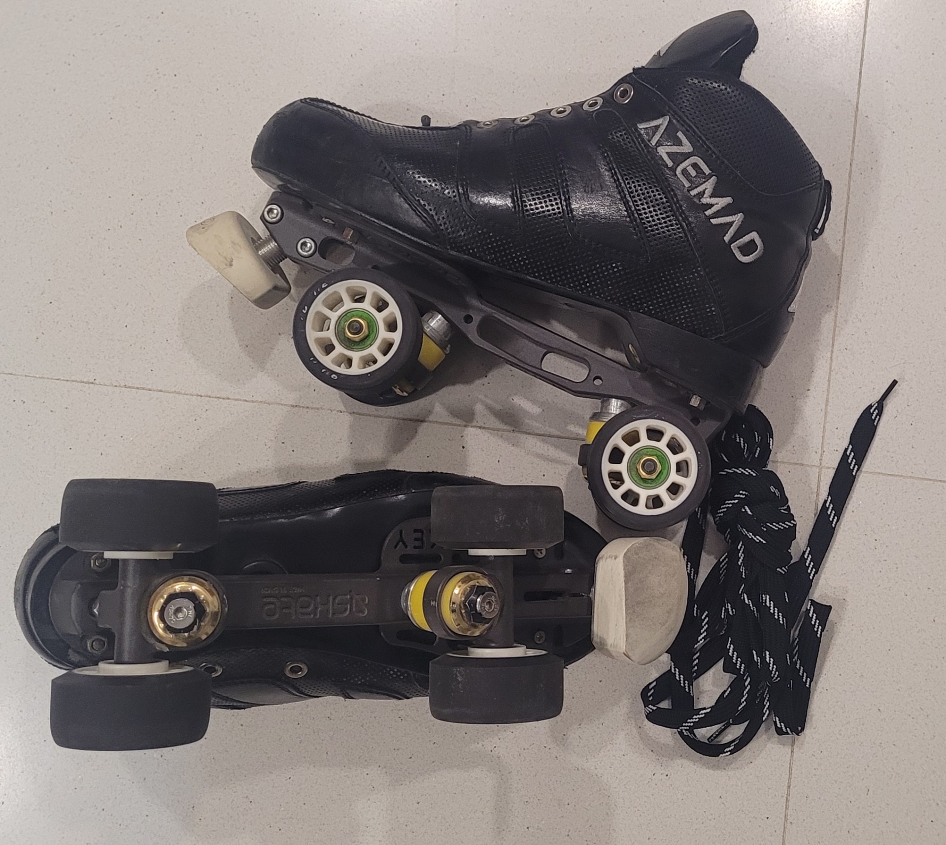 Patins de rodas pretos e brancos com cordas pretas e brancas sobre chão claro